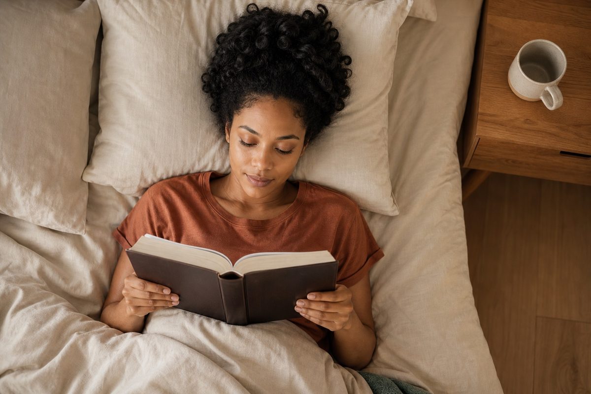 A woman reading her Bible in bed in the early morning, coffee on the nightstand