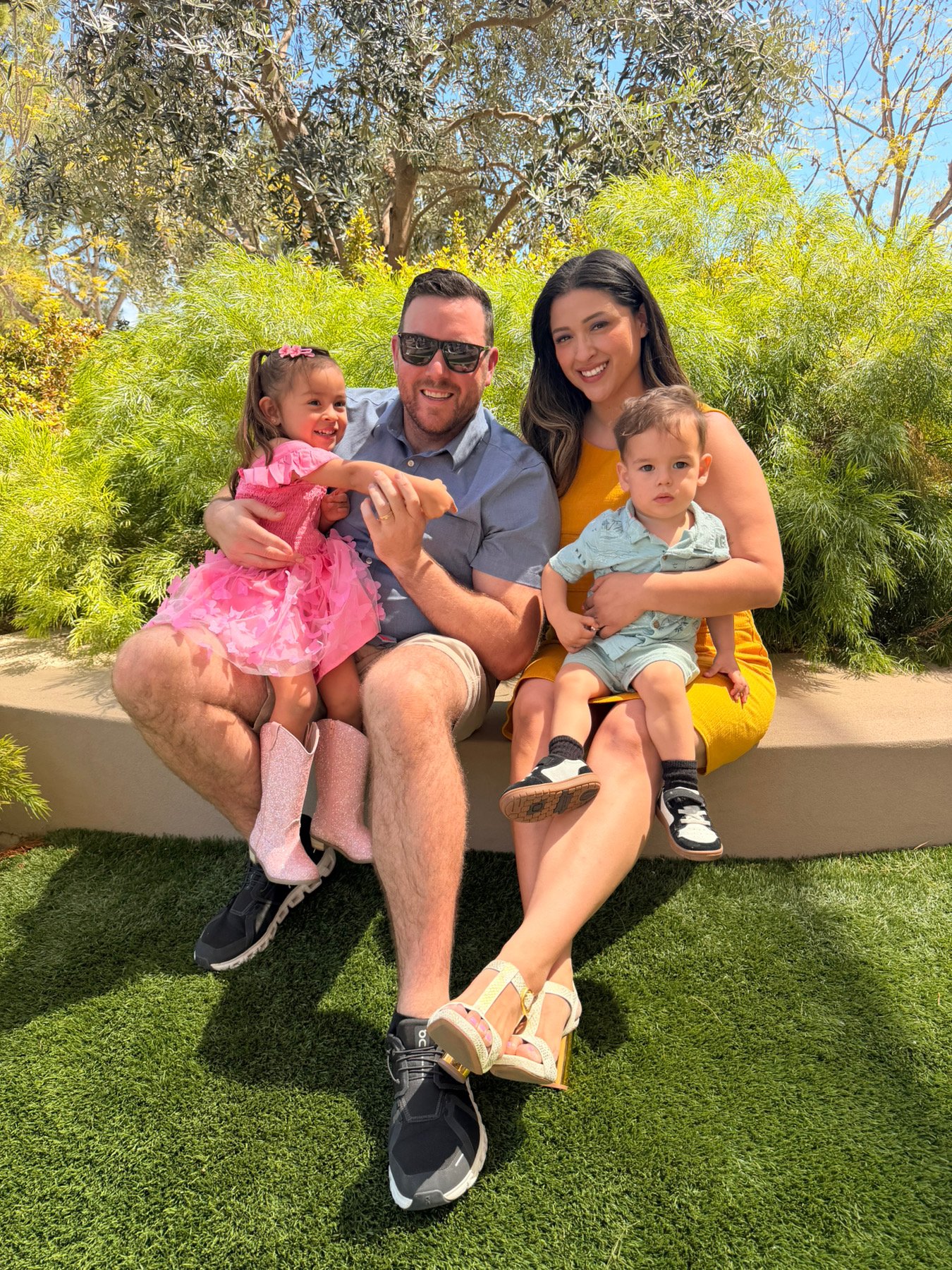 Carol with her husband and their two young children, sitting together outdoors
